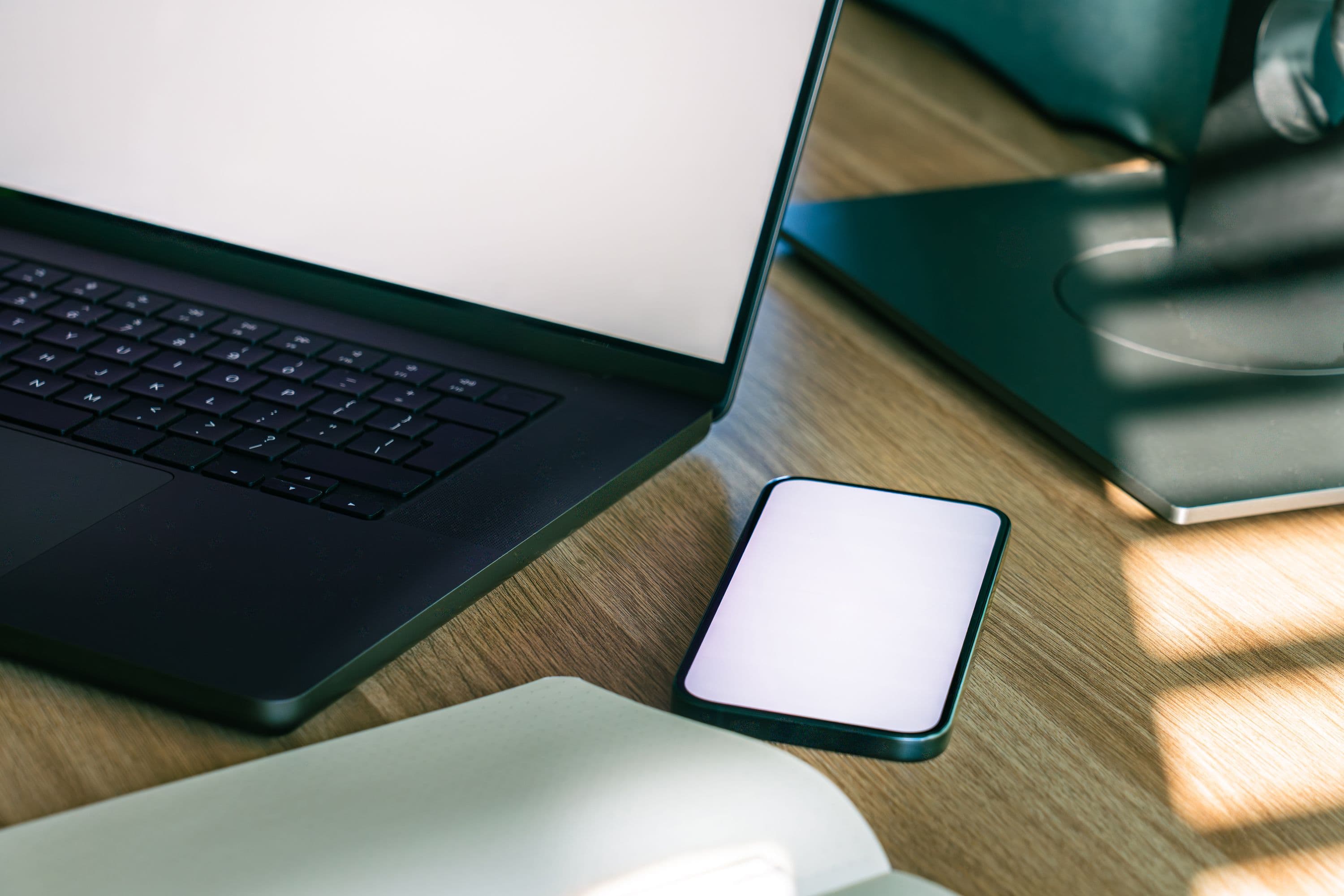 Laptop, phone and desktop workstation arranged in natural light